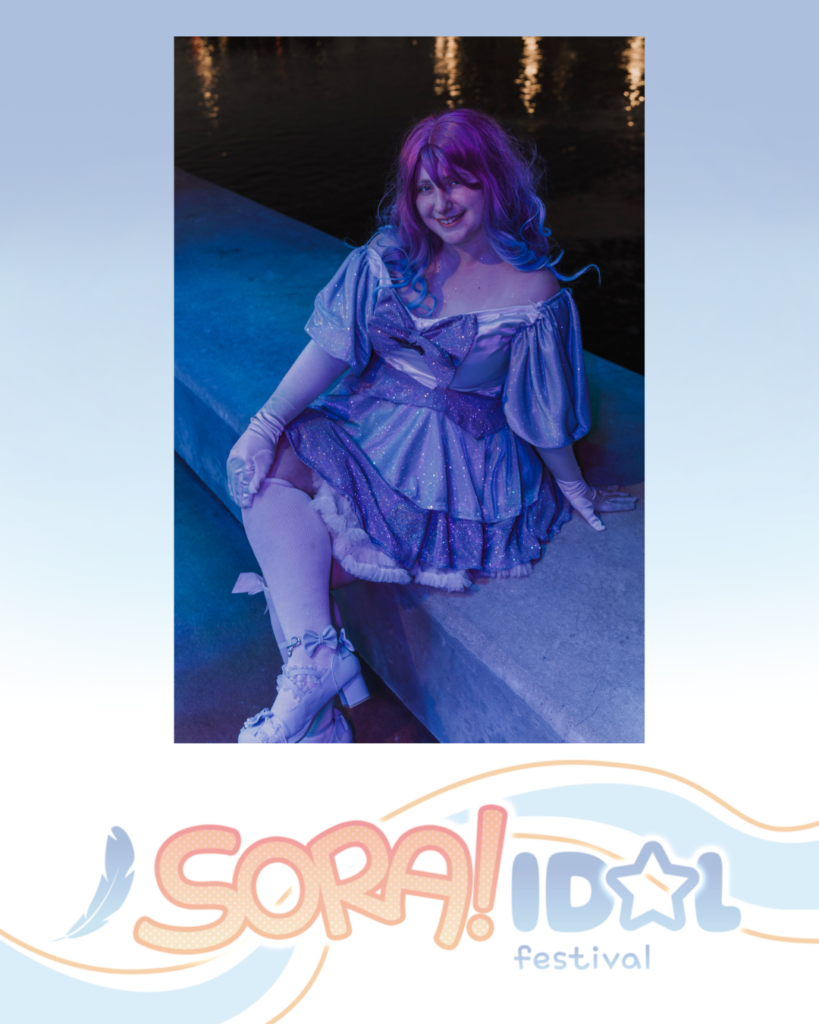 Person in a sparkly purple dress and gloves sitting by water at night under blue and purple lighting